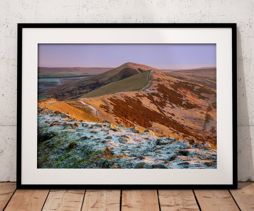 The Great Ridge rises through a light covering of winter snow as early sunlight catches the slopes, Peak District