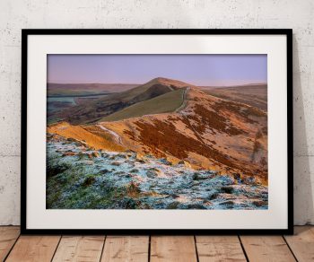 The Great Ridge rises through a light covering of winter snow as early sunlight catches the slopes, Peak District