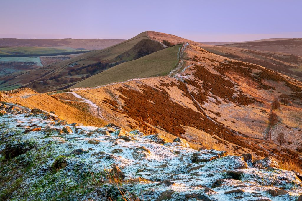 The Great Ridge rises through a light covering of winter snow as early sunlight catches the slopes, Peak District – view 2