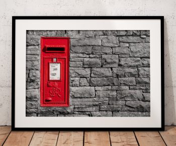 A bright red postbox provides a striking splash of colour against a weathered dry stone wall