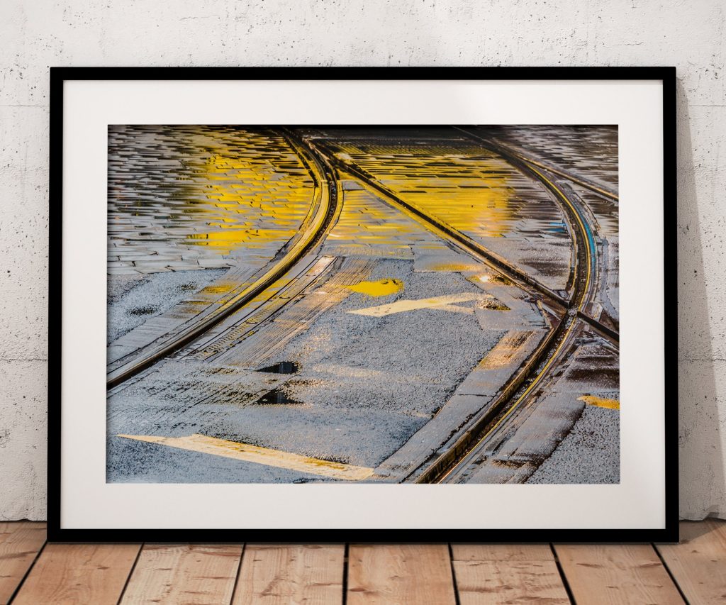 Rain-darkened tram tracks curve through Manchester