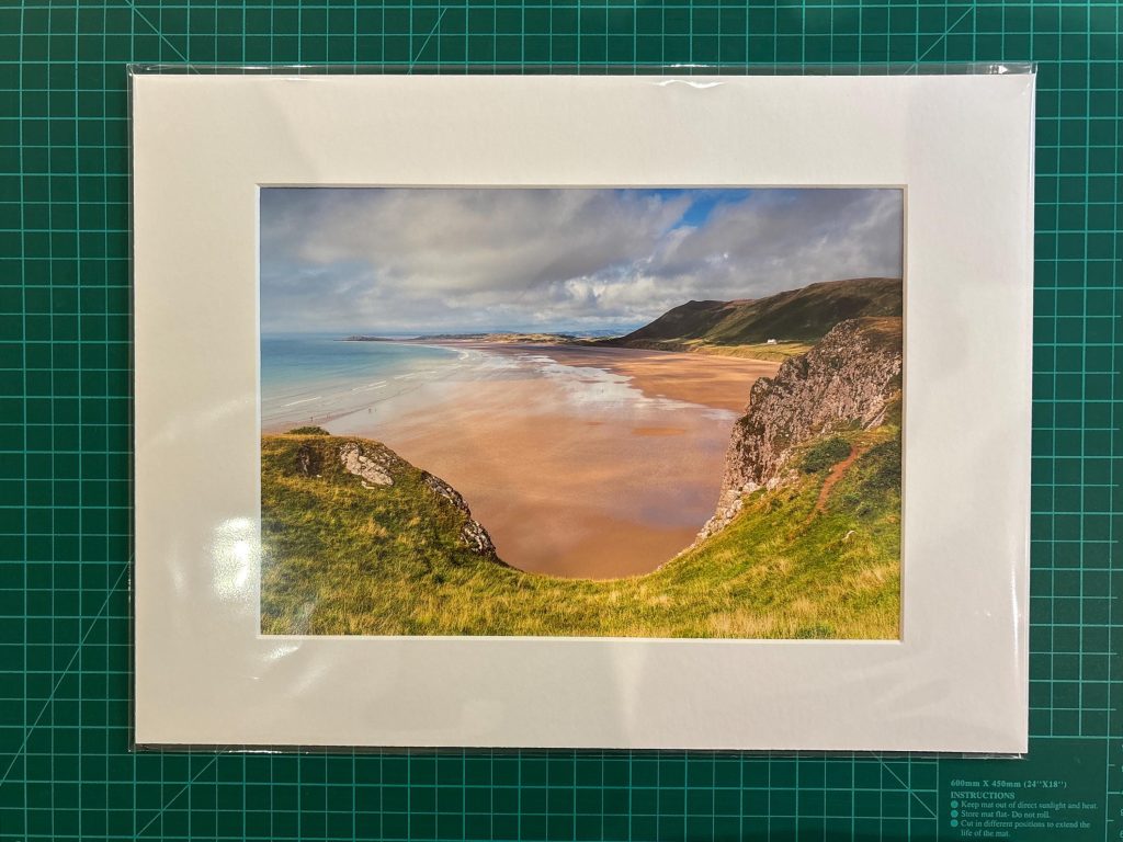 Seen from the cliffs above, Rhossili Beach opens into a wide sweep of golden sand and pale blue sea, Gower – view 3