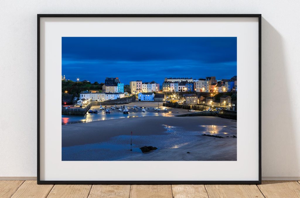 Tenby Harbour takes on a deep blue character after sunset, with the lights of the town, Wales