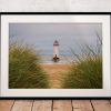 Seen through marram grass on the dunes, Talacre Lighthouse stands quietly against the open shoreline of the Dee Estuary