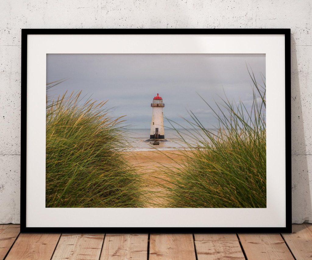 Seen through marram grass on the dunes, Talacre Lighthouse stands quietly against the open shoreline of the Dee Estuary
