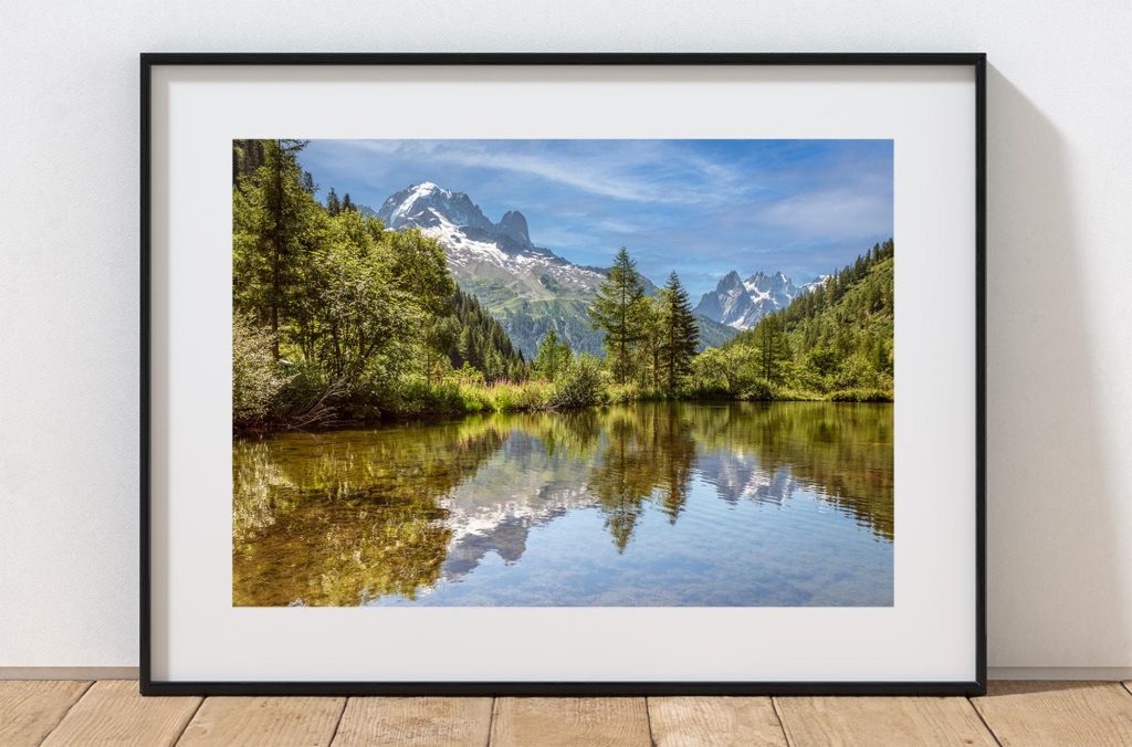 The calm surface of a mountain lake near Col des Montets reflects the surrounding peaks, France