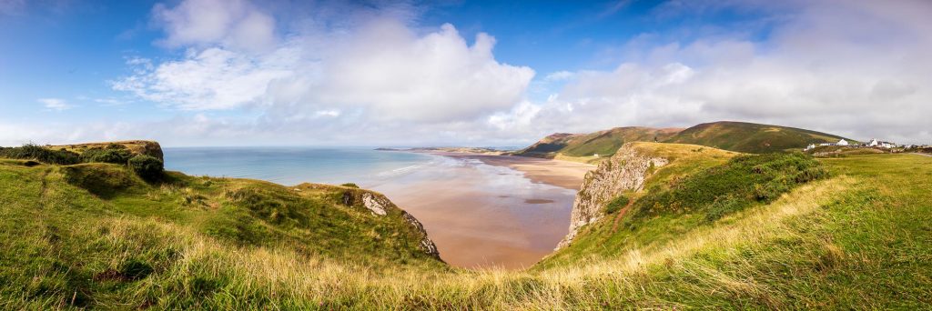 Rhossili Bay opens out across the Gower Peninsula in this panoramic coastal photograph