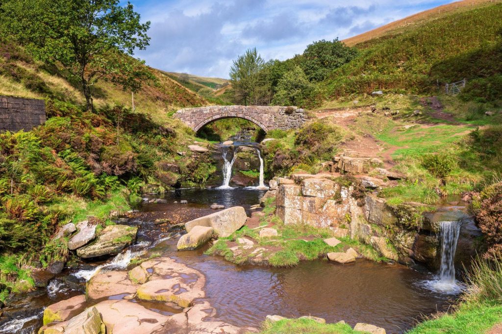 The packhorse bridge at Three Shires Head spans a small pool between waterfalls in the Peak District – view 2