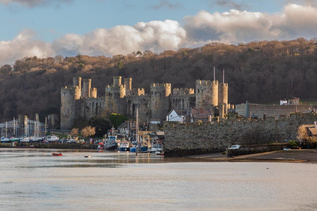 As the sun falls, warm light catches the walls and towers of Conwy Castle, North Wales – view 2