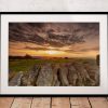 A dry-stone wall leads across the foreground as the sun sets over the Cheshire Plain, with Kerridge Ridge