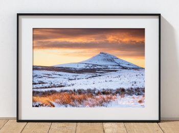 Shutlingsloe rises above the snowy moorland of the western Peak District as the first sunlight reaches the hills