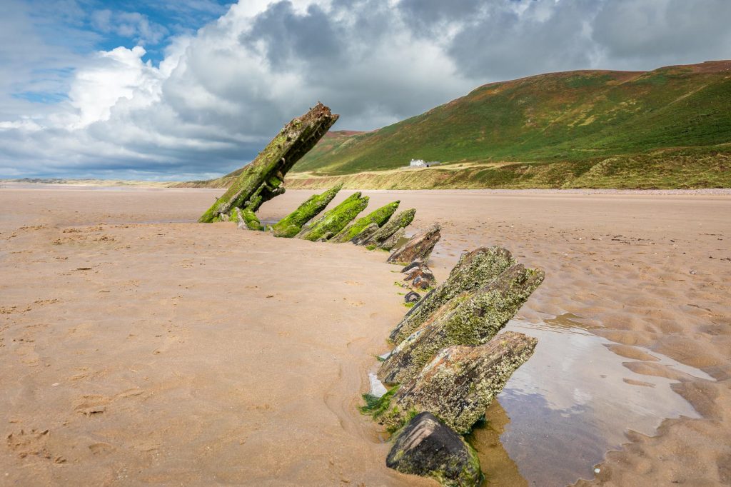 The weathered timbers of the Helvetia rise from the sands of Rhossili Beach, Wales – view 2