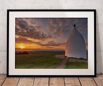 White Nancy stands on Kerridge Ridge above Bollington as the setting sun fills the evening sky with warm colour