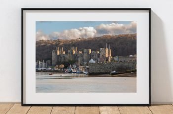 As the sun falls, warm light catches the walls and towers of Conwy Castle, North Wales