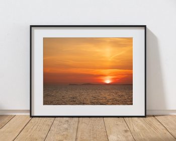 From Little Haven, the sun sinks towards the horizon beyond the St Davids Peninsula, filling the sky, Wales
